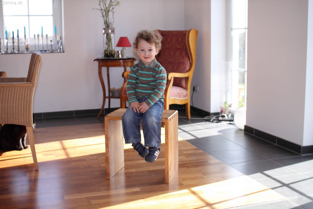 Junge sitzt in Wohnzimmer auf einer schönen Holzbank